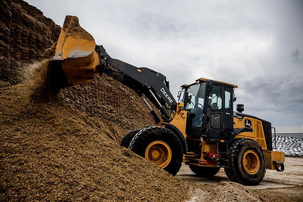 Side left view of a 544G Wheeled Loader pushing material atop a large pile
