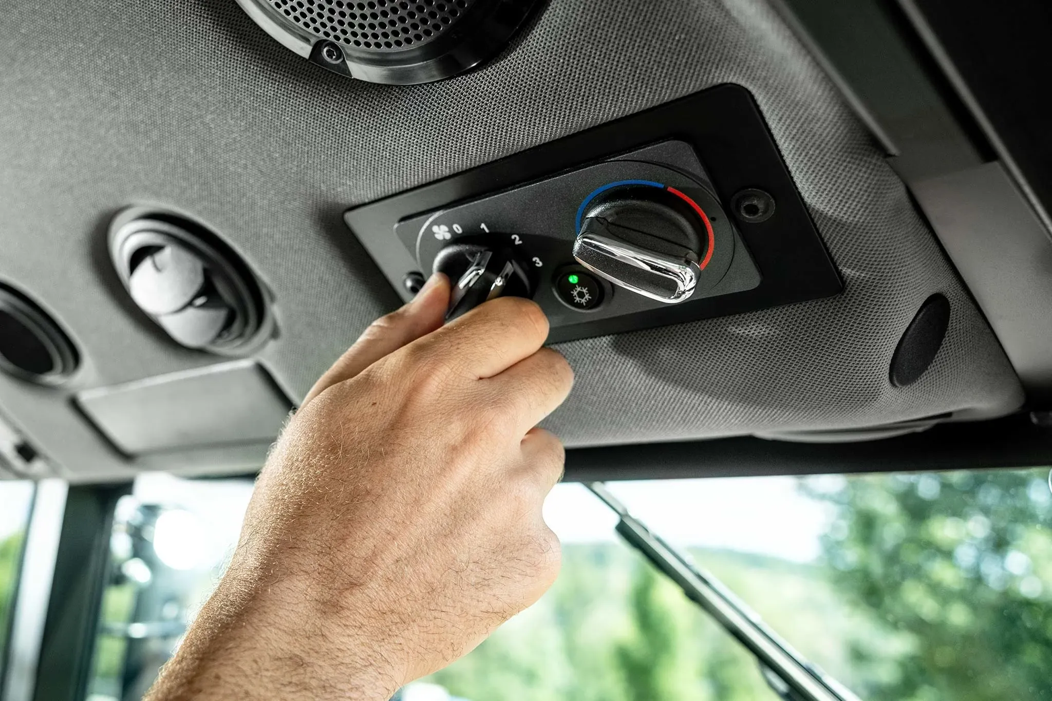 Hand adjusting the ventilation and temperature controls inside a John Deere tractor cab