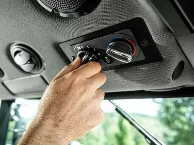 Hand adjusting the ventilation and temperature controls inside a John Deere tractor cab