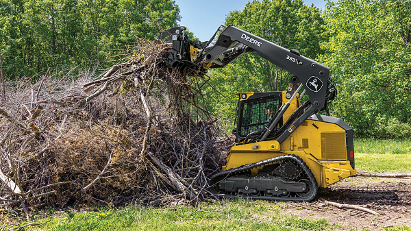 333 P-Tier compact track loader using a grapple attachment to clear a pile of branches.