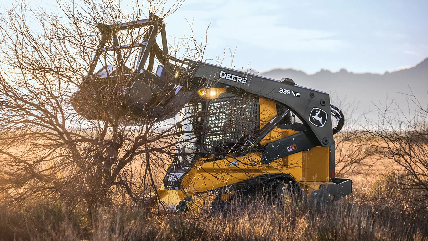 335 P-Tier compact track loader using a mulching head attachment to clear brush.