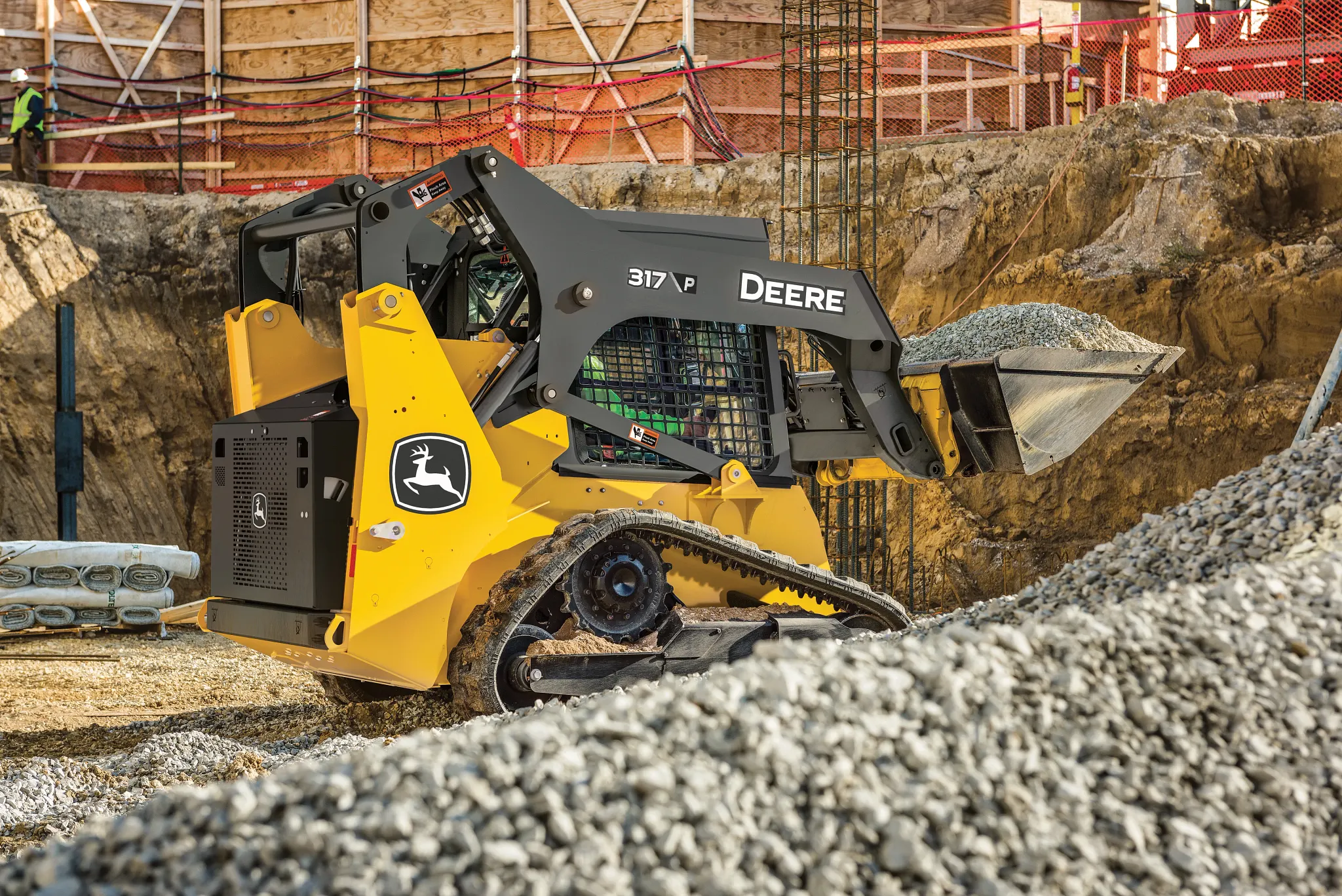 A 317 P-Tier Compact track Loader moving rocks on a construction site