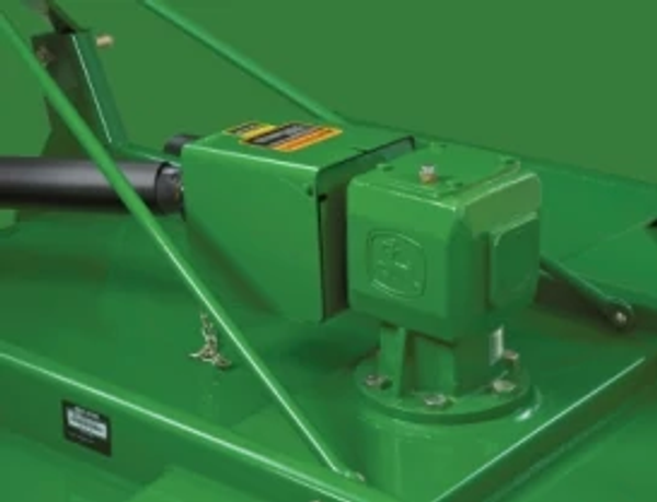 Close-up of a green mechanical gearbox and driveline assembly on a John Deere rotary cutter