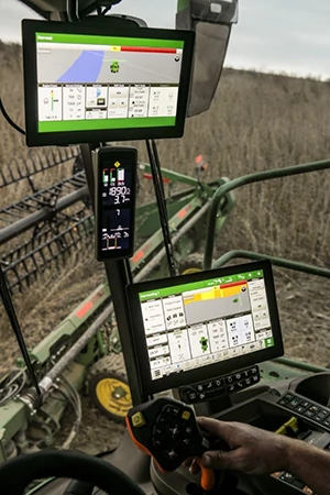 Front, angled view of the two-screen G5Plus CommandCenter™ extended monitor setup inside a cab with a field of crop through the windows in the background