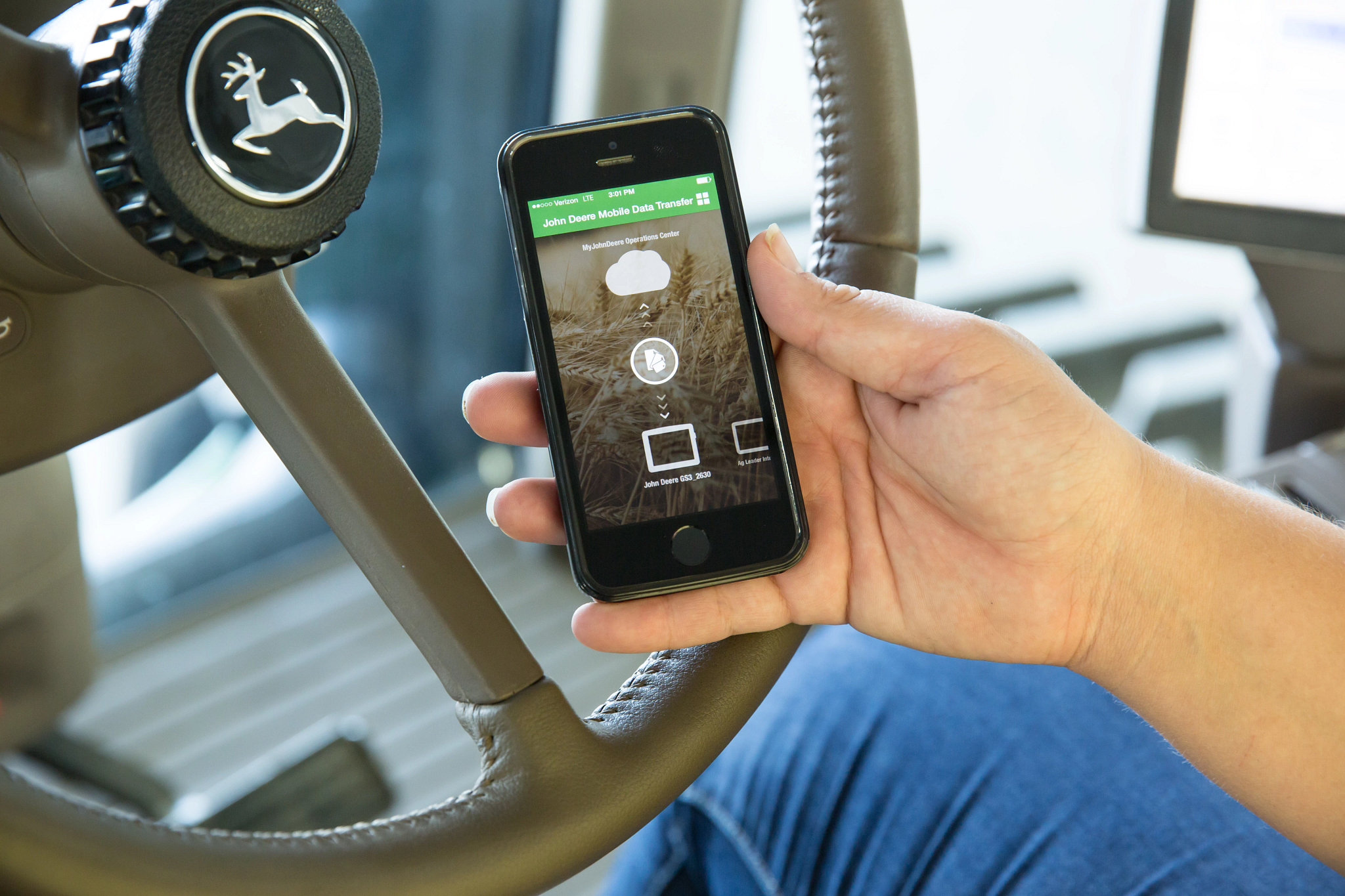 Hand holding an iPhone in front of a steering wheel inside a cab with Mobile data transfer screen up