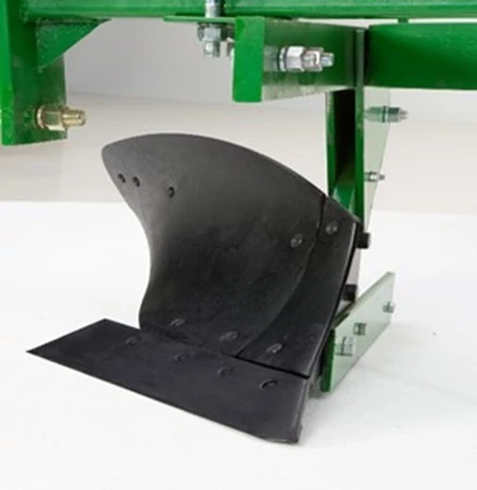 Close‑up of a black curved plow blade mounted to a green agricultural implement frame, showing the steel cutting surface, mounting bracket, bolts, and support plate.