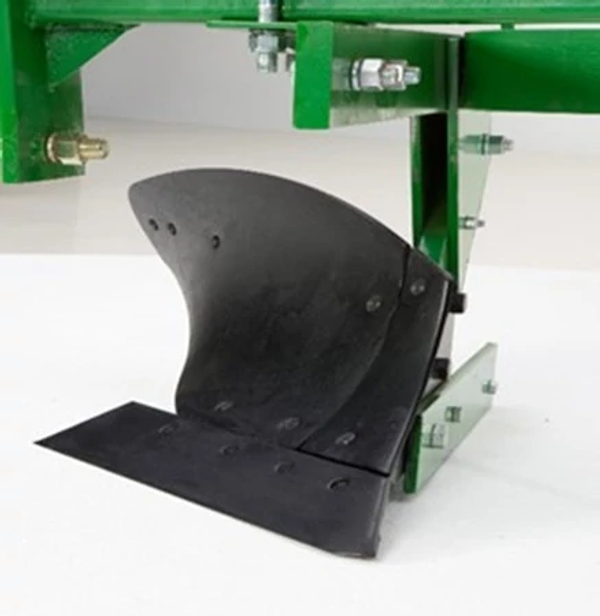 Close‑up of a black curved plow blade mounted to a green agricultural implement frame, showing the steel cutting surface, mounting bracket, bolts, and support plate.