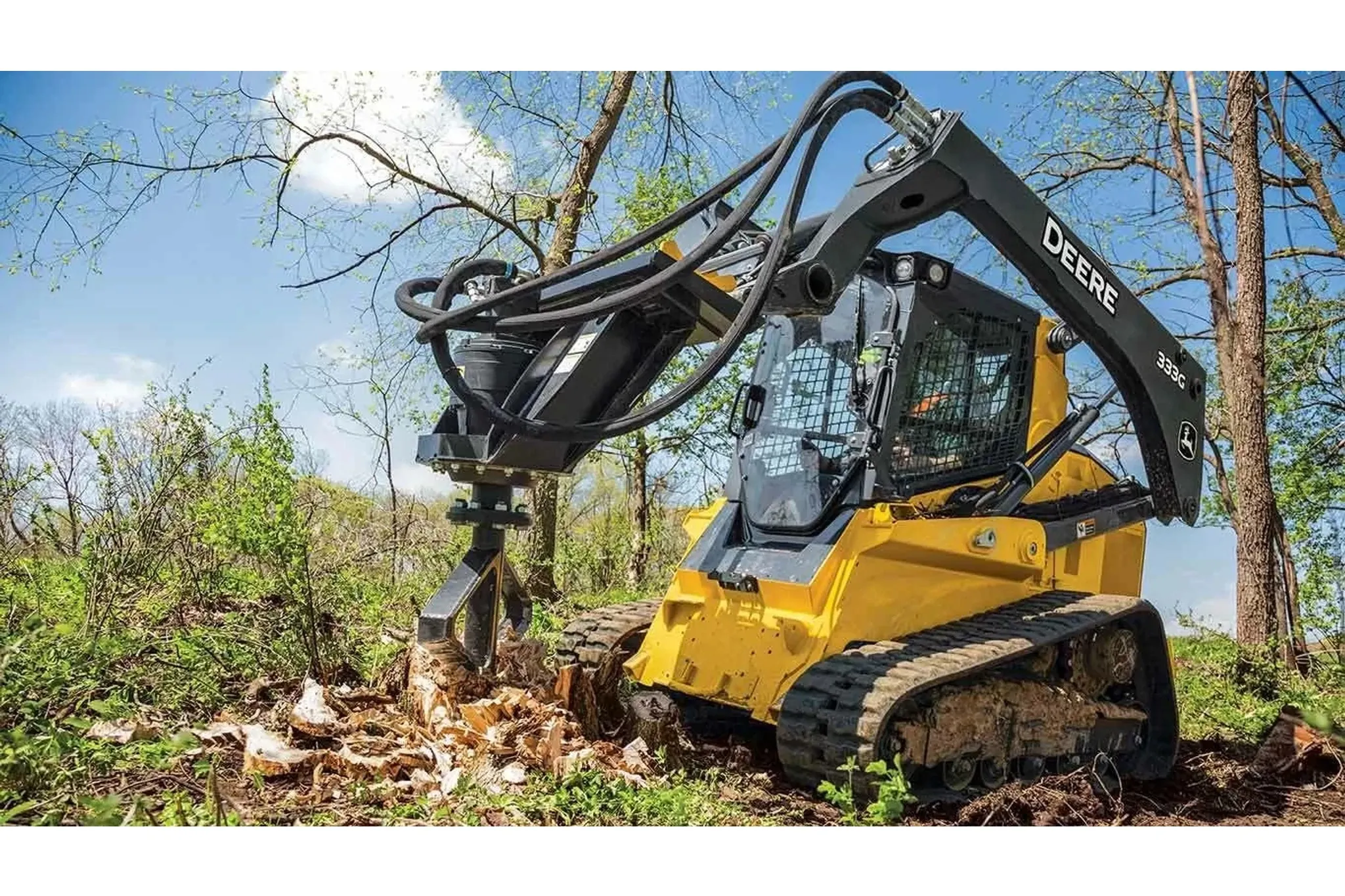 Front left view of 333G Compact Track Loader with SS30 Stump Shredder shredding a stump in a cleared field