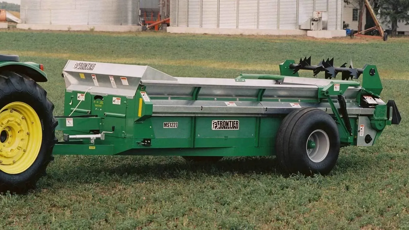 MS12 Series Manure Spreader on grass with bins behind it