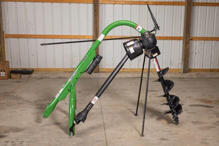 Side view of a post hole digger with green hook-up parking stand set up in a workshop