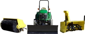 Studio view of a tractor with attached front blade and a yellow broom and snow blower waiting at the ready on either side