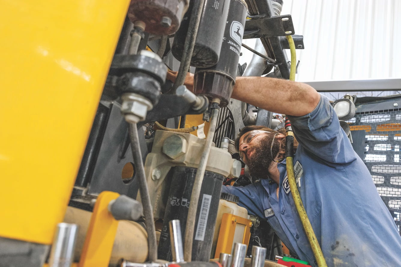 John Deere service technician working on engine