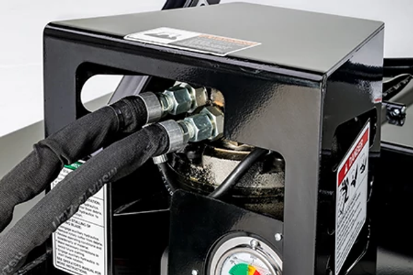 Close-up of a black metal hydraulic power unit housing with two connected hydraulic hoses, fittings, and warning labels, shown against a neutral background