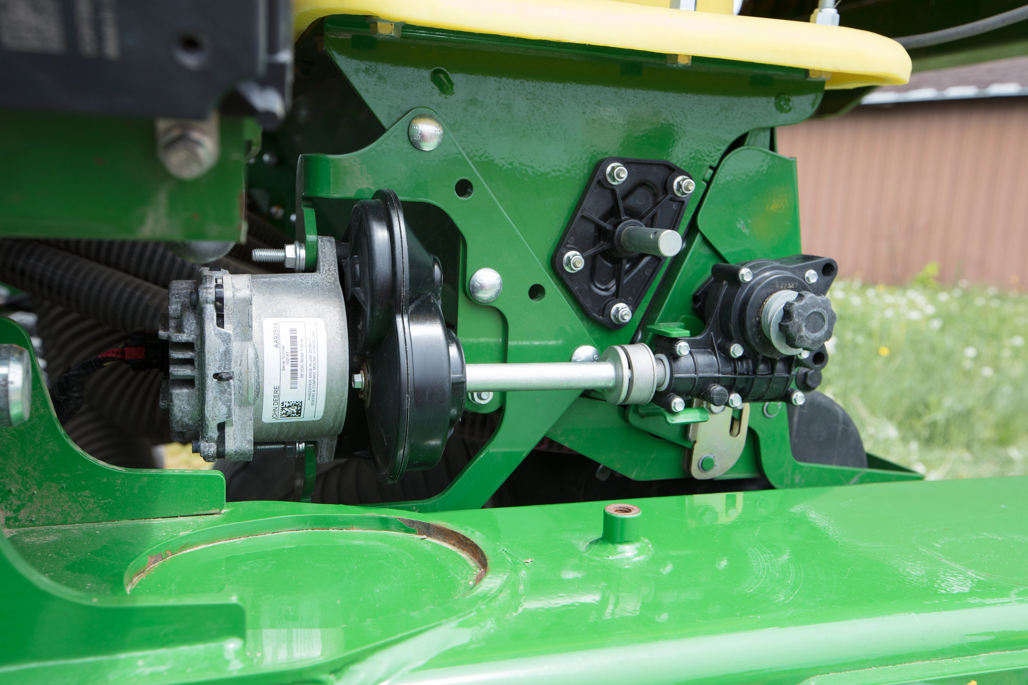 Close-up showing SectionCommand™ mechanical components including a drive shaft, round black pulleys, a motor unit, mounting bolts, and connected linkages