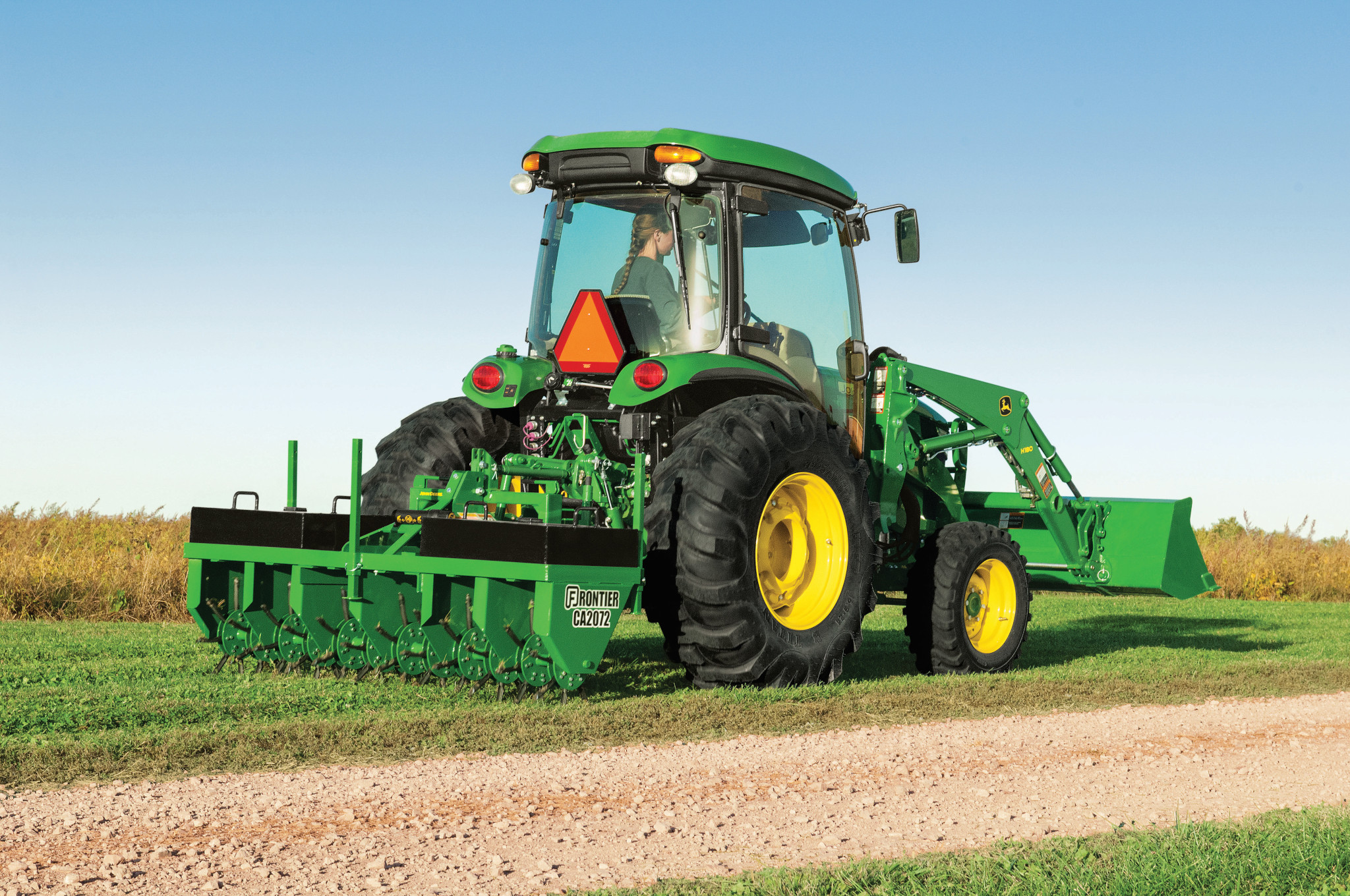 John Deere 4066R cab tractor with loader and rear core aerator working on turf