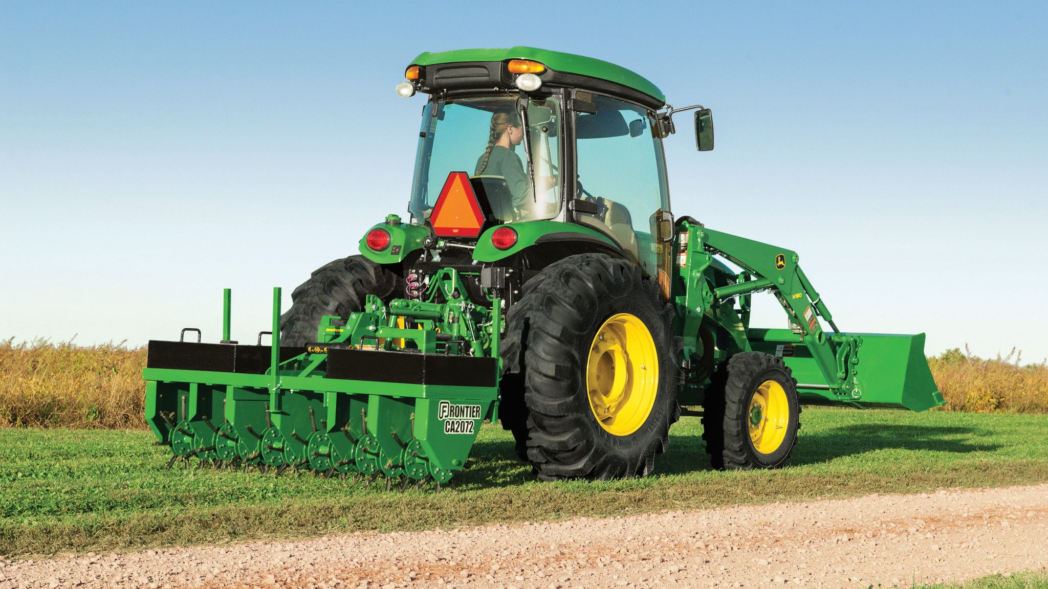 John Deere 4066R cab tractor with loader and rear core aerator working on turf