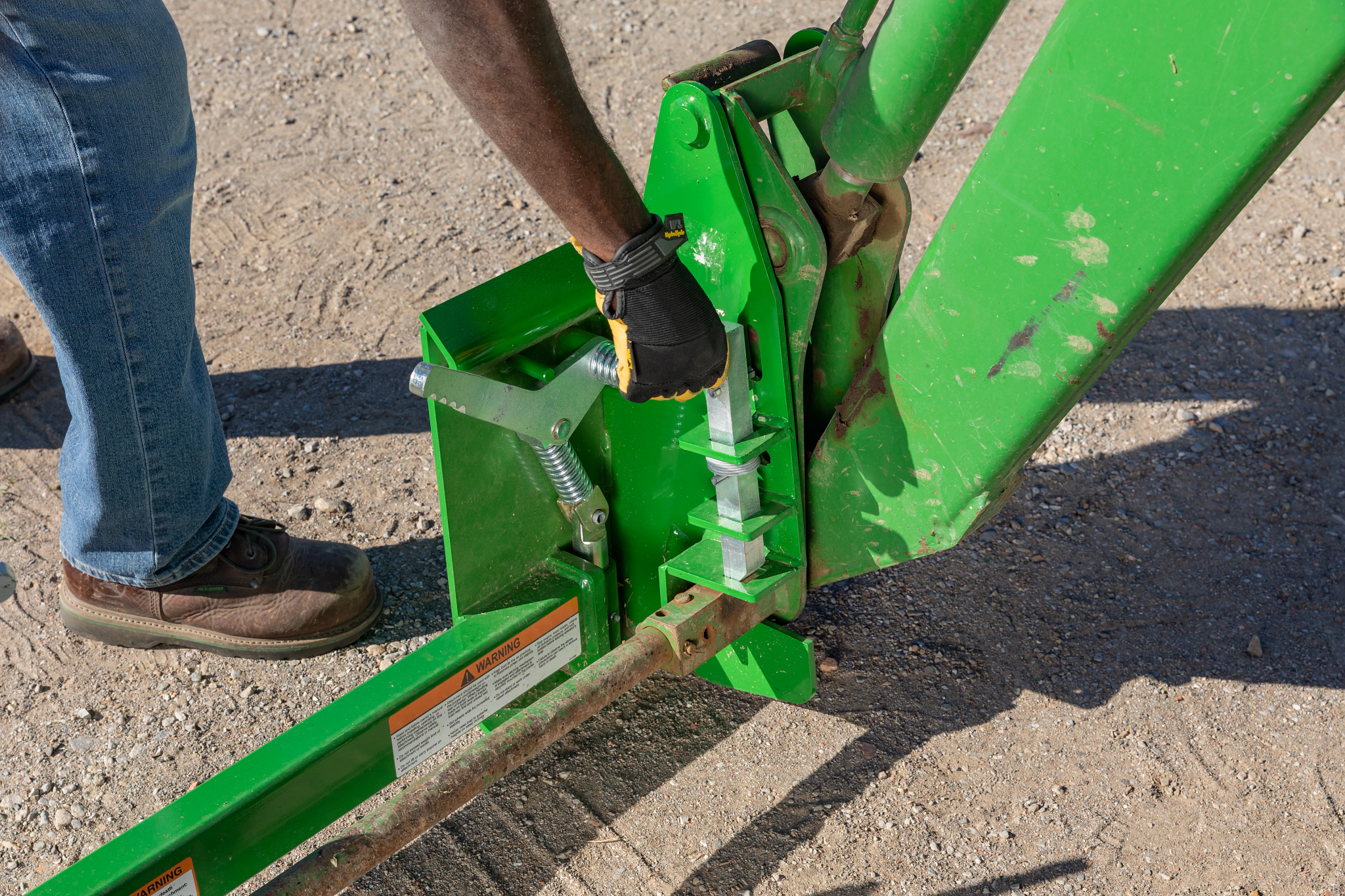Gloved hand locking the SA22D loader carrier adapter in place on a loader