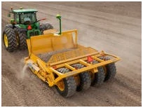 Rear left view of a tractor pulling a scraper with iGrade™ leveling capabilities across a dirt lot