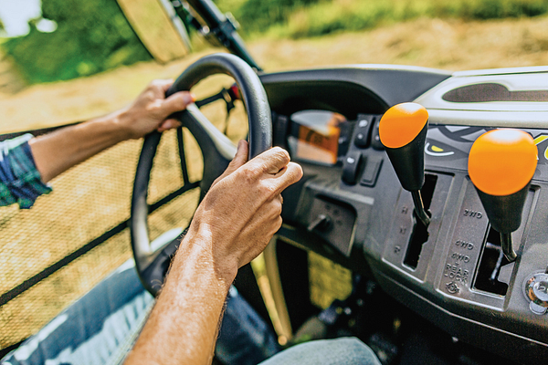 Side right view of the dash and steering wheel of an XUV560E Mid-Size Crossover Utility Vehicle, two hands steering