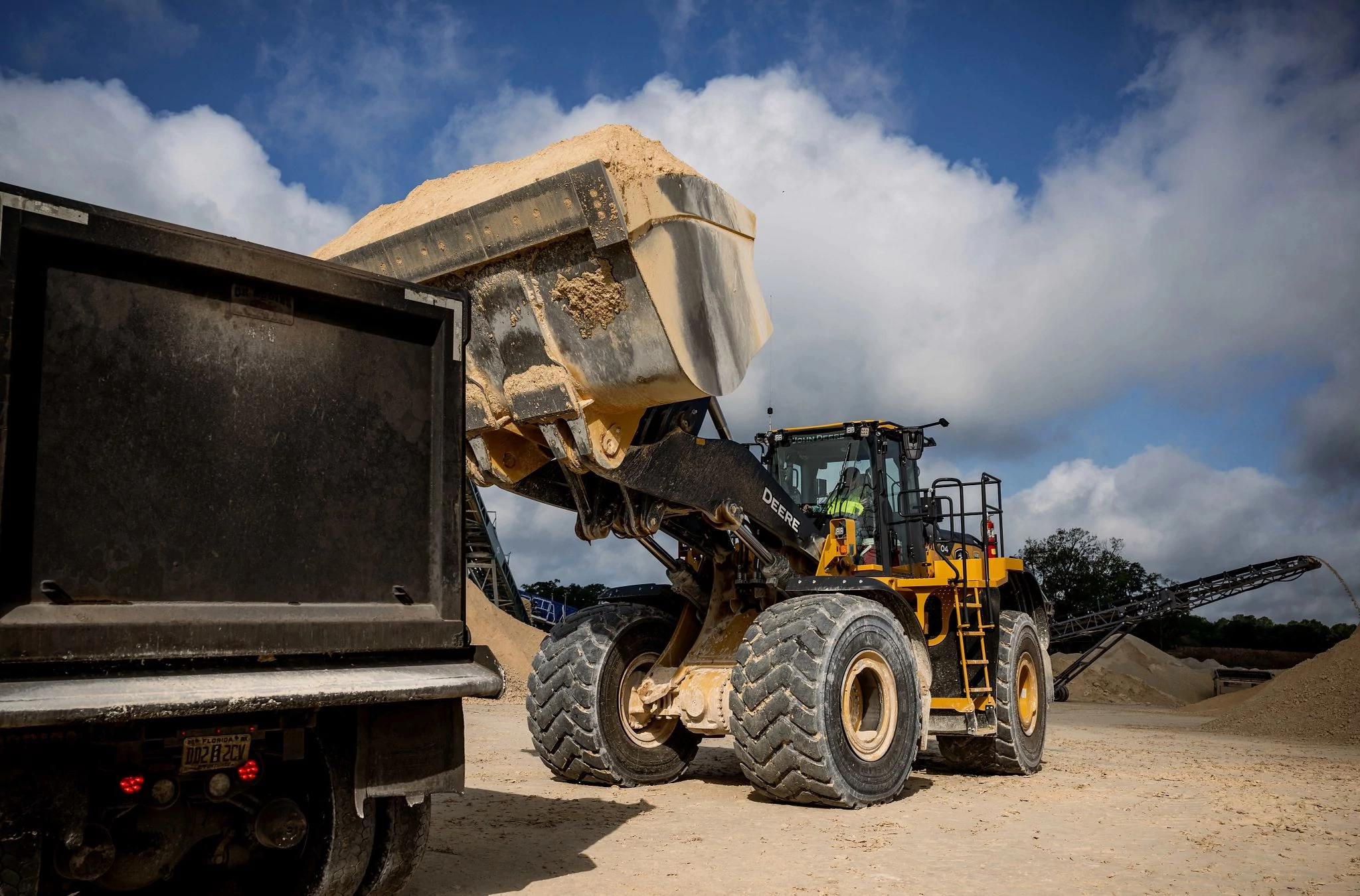 904 P-Tier Wheel Loader in a gravel yard ready to dump a load of dirt into a black dump truck