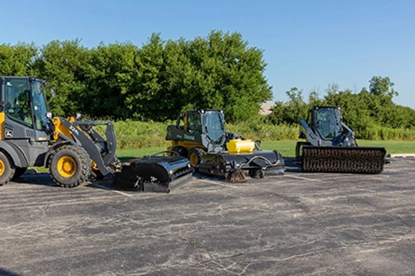 Front view of skid steers and a loader lined up on pavement with BA96C angled broom, BP84C Pick-Up Broom, and BP84C Pick-Up Broom attachments