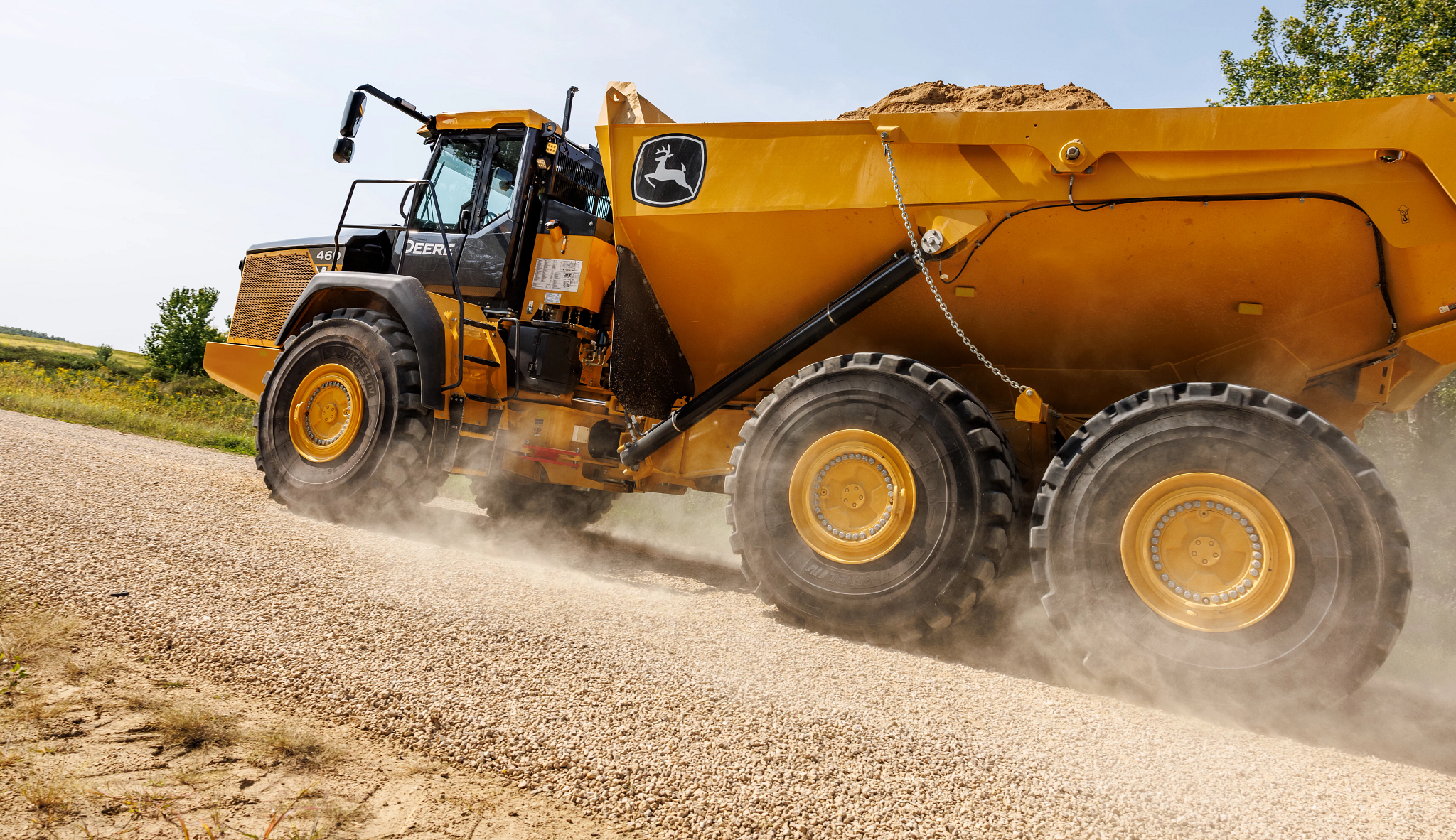 Left side view from the roadside of a loaded 460 P-Tier articulated dump truck driving by