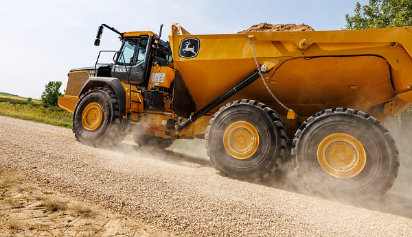 Left side view from the roadside of a loaded 460 P-Tier articulated dump truck driving by