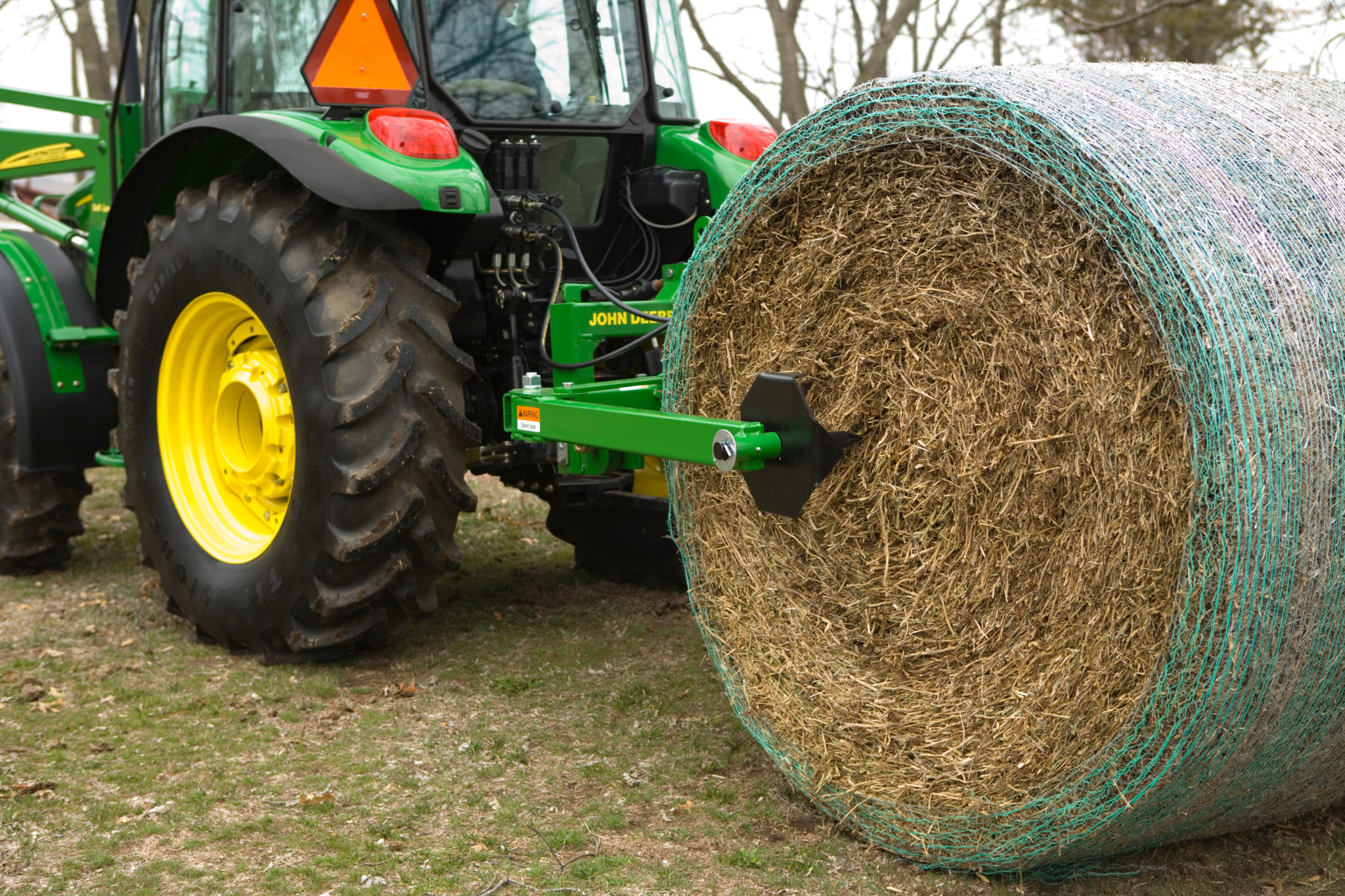 Rear left view of BU10 Bale Unroller hitched to a tractor and holding a bale in a field