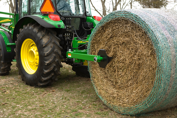 Rear left view of BU10 Bale Unroller hitched to a tractor and holding a bale in a field