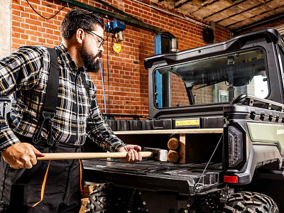 A man places a toolbox into a utility vehicle, readying for work or maintenance activities.
