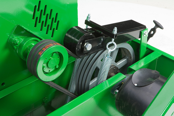 Close-up of wood chipper showing a belt‑driven pulley system with springs, tensioners, and protective guards