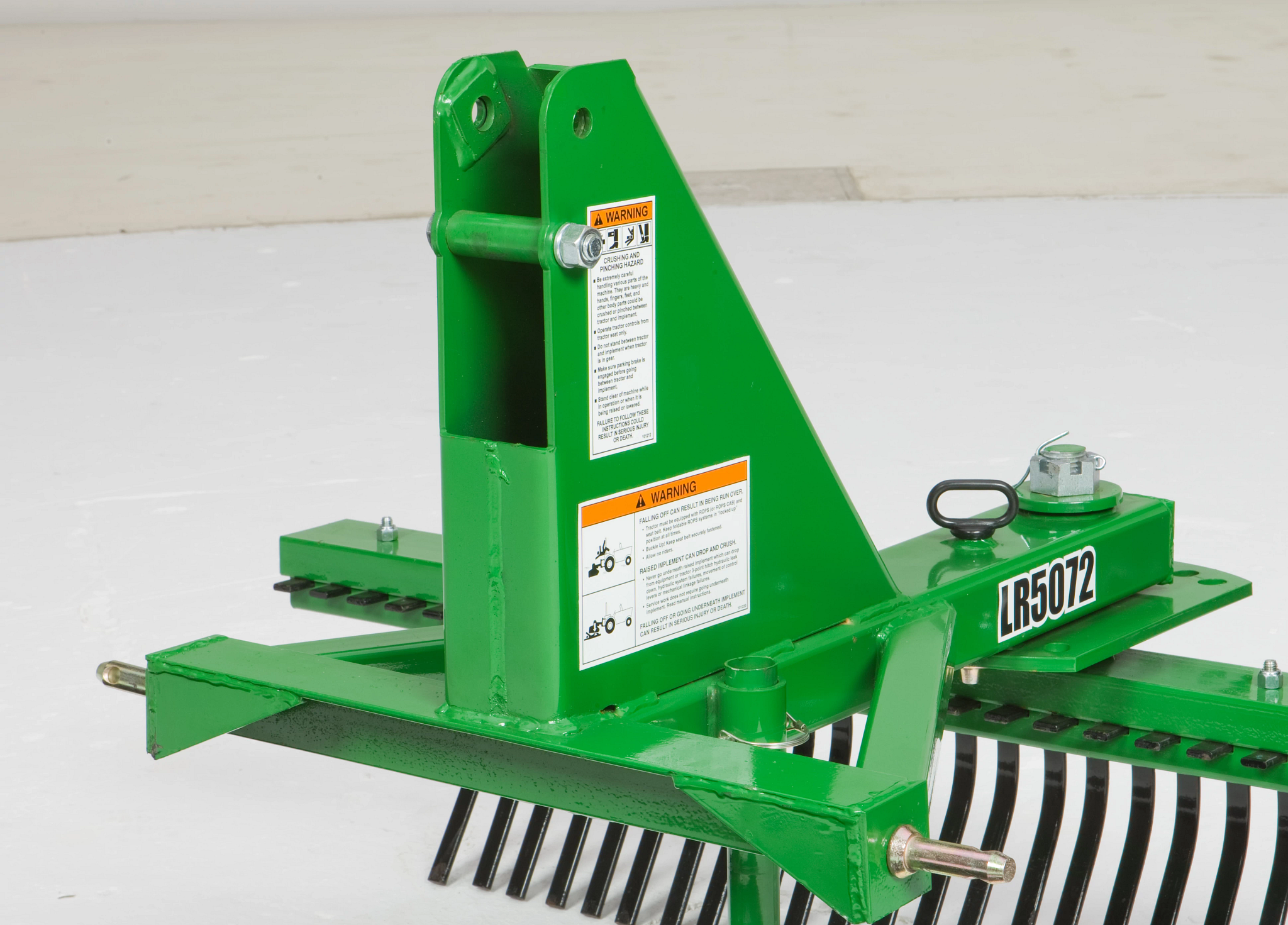 Rear right studio view of a green LR5072 landscape rake's hitch hookup