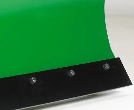 Close-up of a green curved metal blade featuring a black reinforced cutting edge secured with bolts