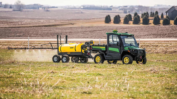 New John Deere Gator XUV 845R Signature Series Utility Vehicle with StarFire receiver moving through a field with dust swirling with a golden sunset look to the photo