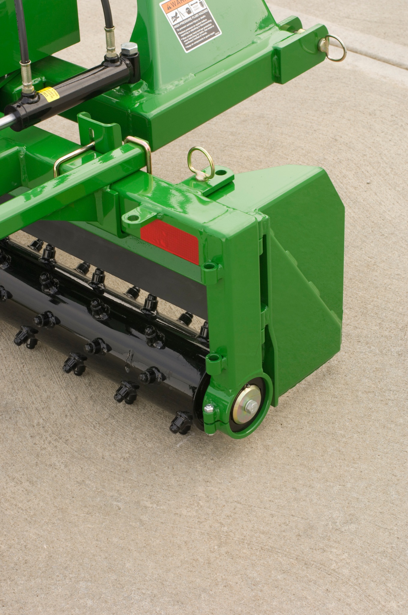 Close-up of PR11 Power Series Rake showing adjustable end plate with hydraulic lines and a roller with multiple blades underneath