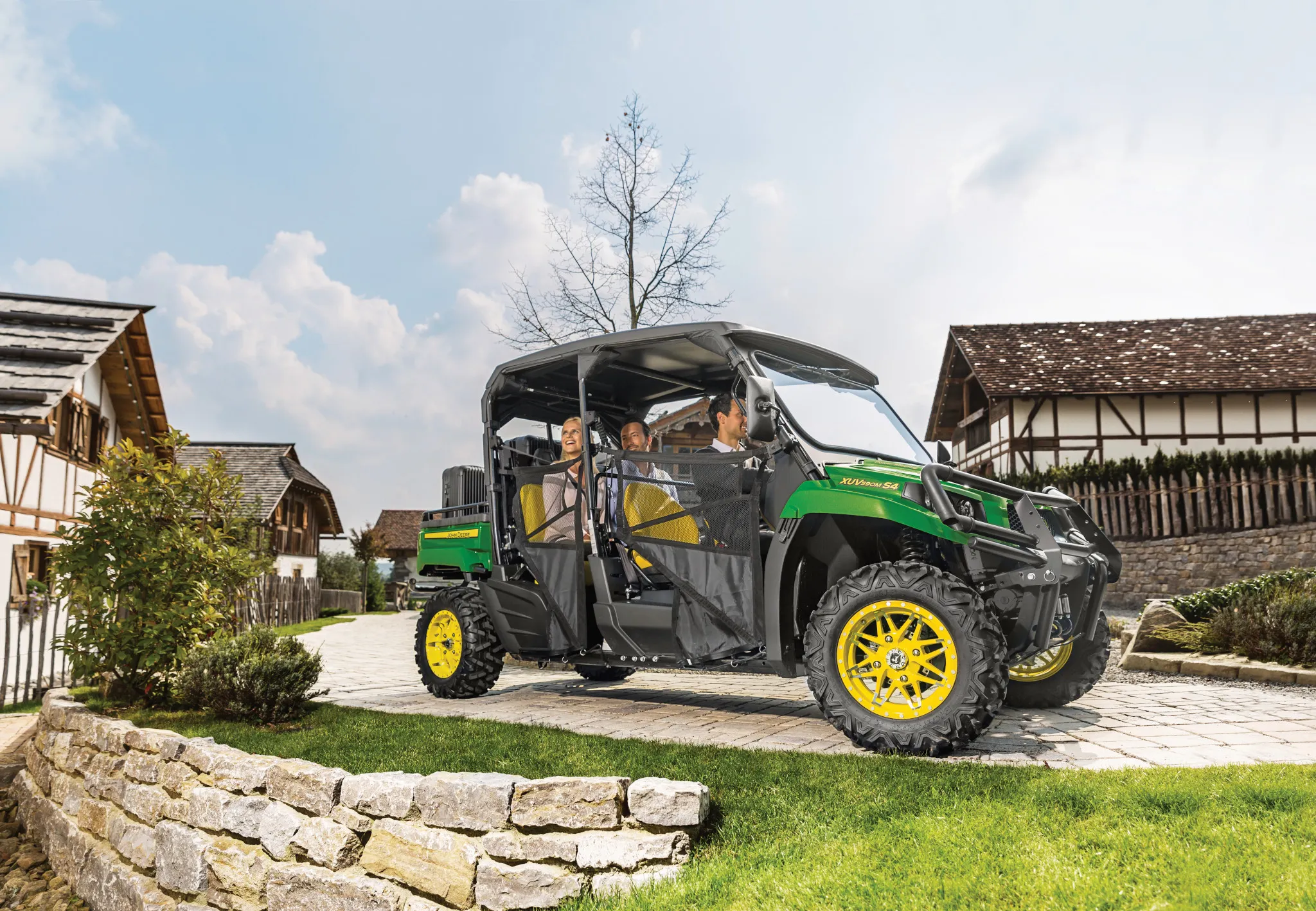 Side right view of an XUV590M S4 Gator with three passengers driving through a neighborhood