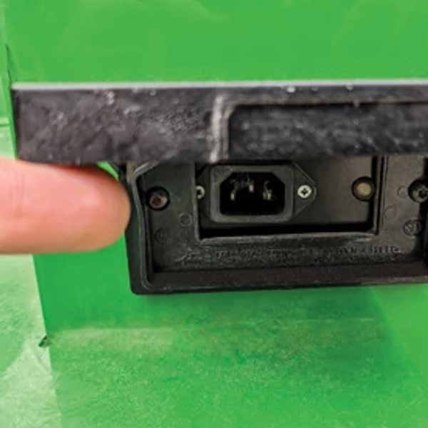 Close-up of a finger lifting the LED charge indicator on a TE Electric Gator to access IEC connector for charging.