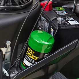 Close-up of a green “Easy Change” oil filter mounted inside an engine compartment next to a black battery and surrounding hoses and wiring.