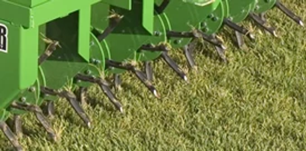 Close-up of a CA20 core aerator's eight spoons per hub digging into grass