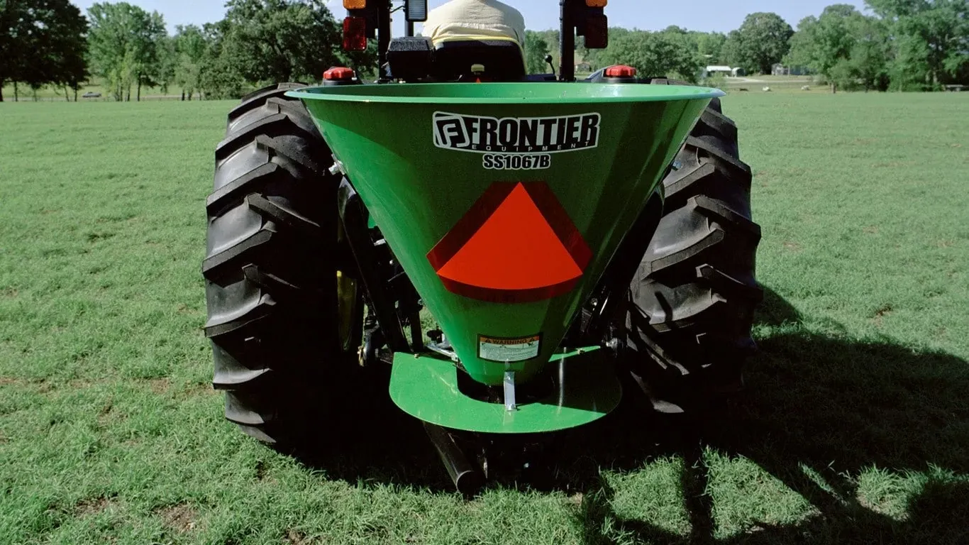 Seeding Equipment SS10B Broadcast Spreaders with there is a tractor with a large green seeder on the back