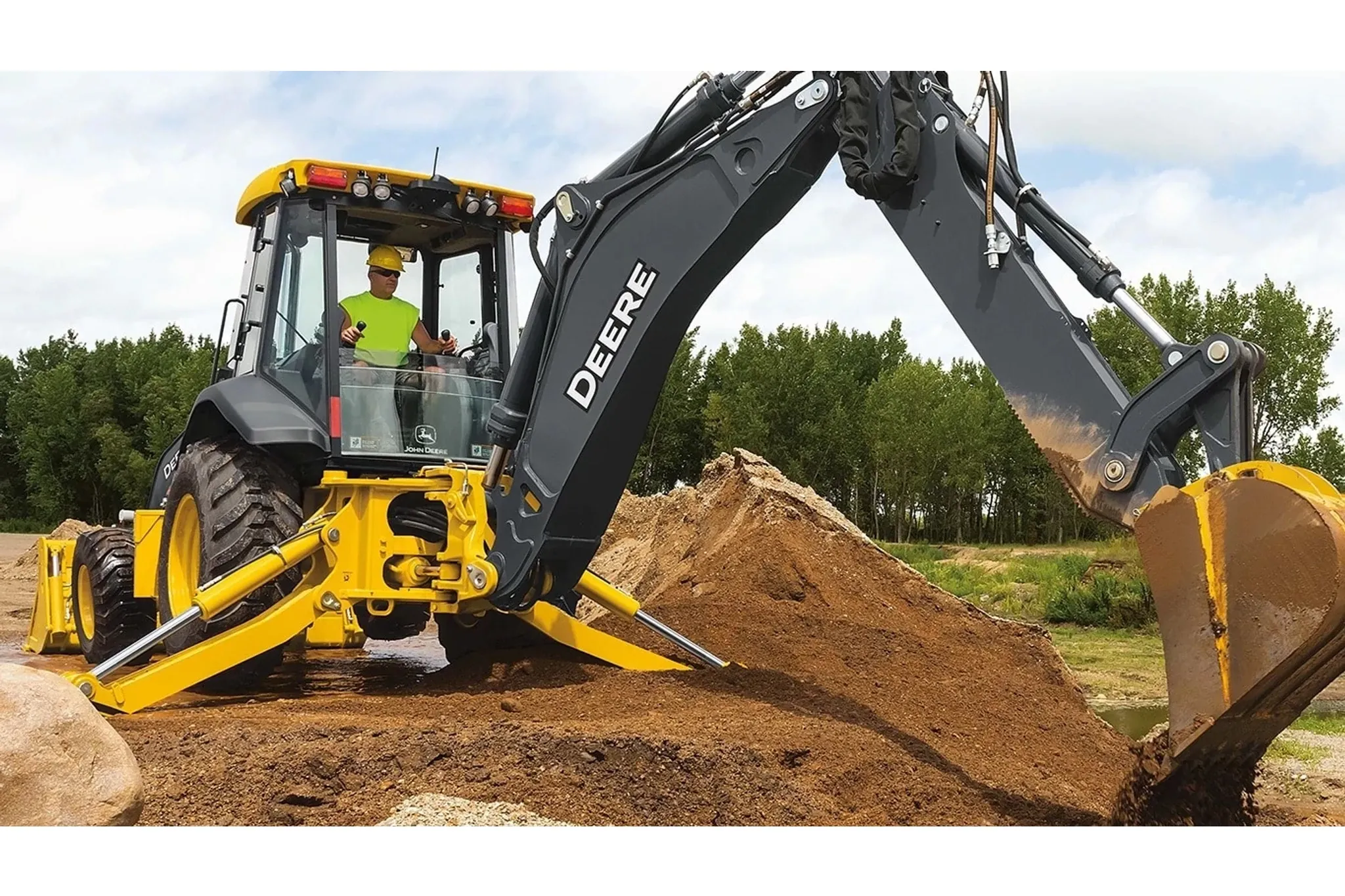 An operating moving large piles of dirt with a 710 P-Tier Backhoe