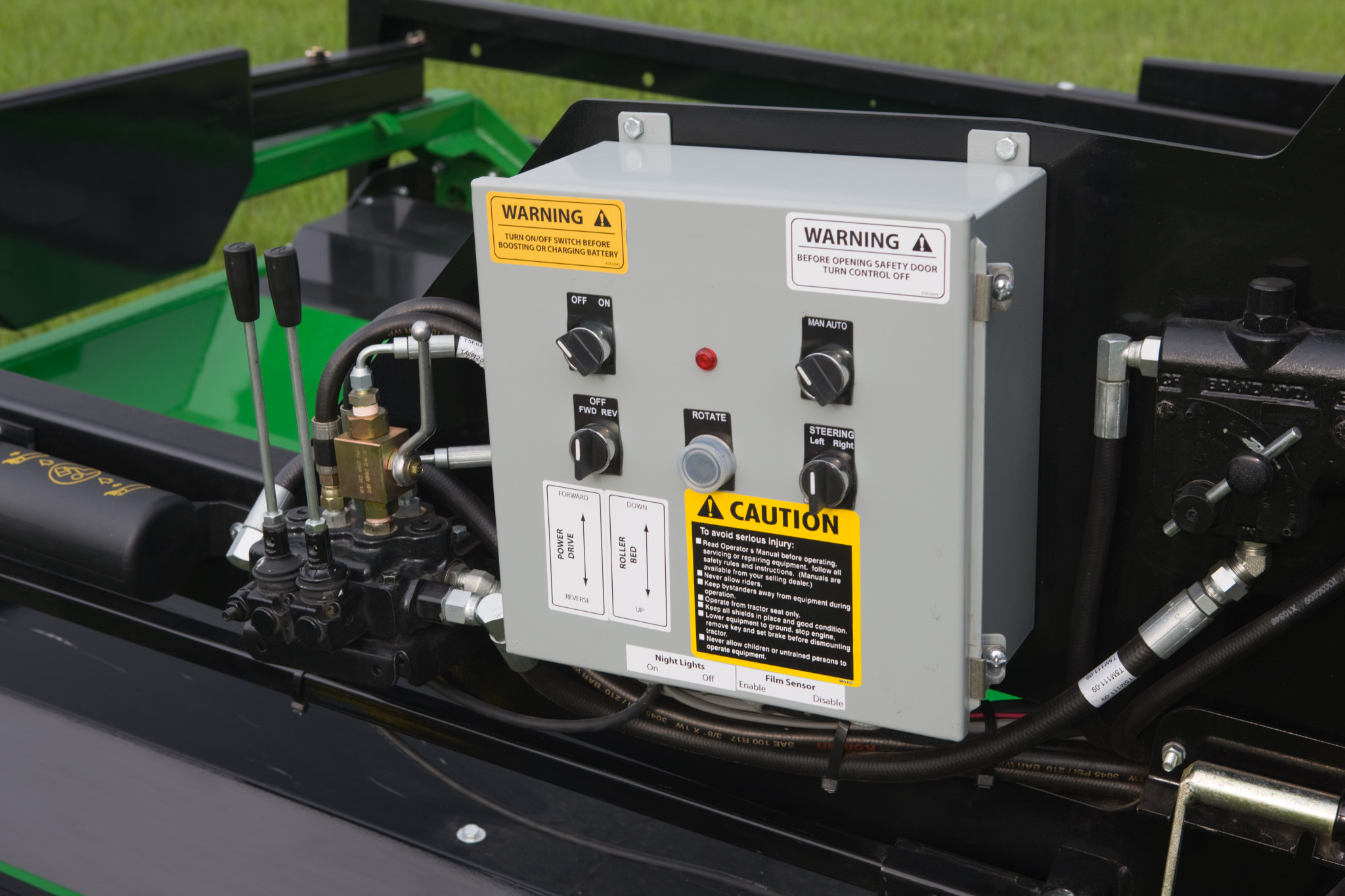 Front view of an LW1266 inline bale wrapper's gray control box and levers, located atop the machine
