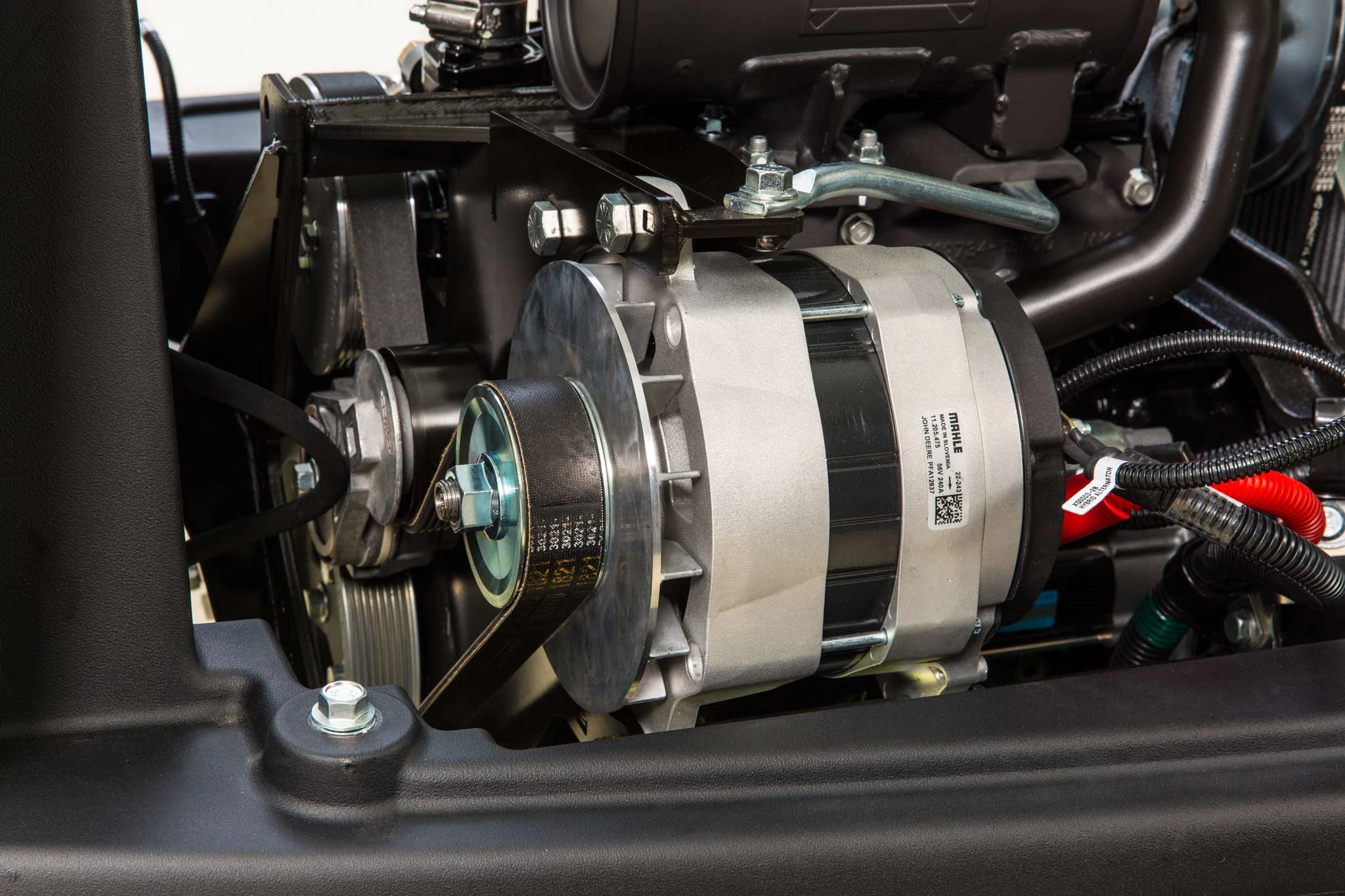 Studio close-up of a Fairway Mower's alternator nestled amongst cables, bolts, and housing