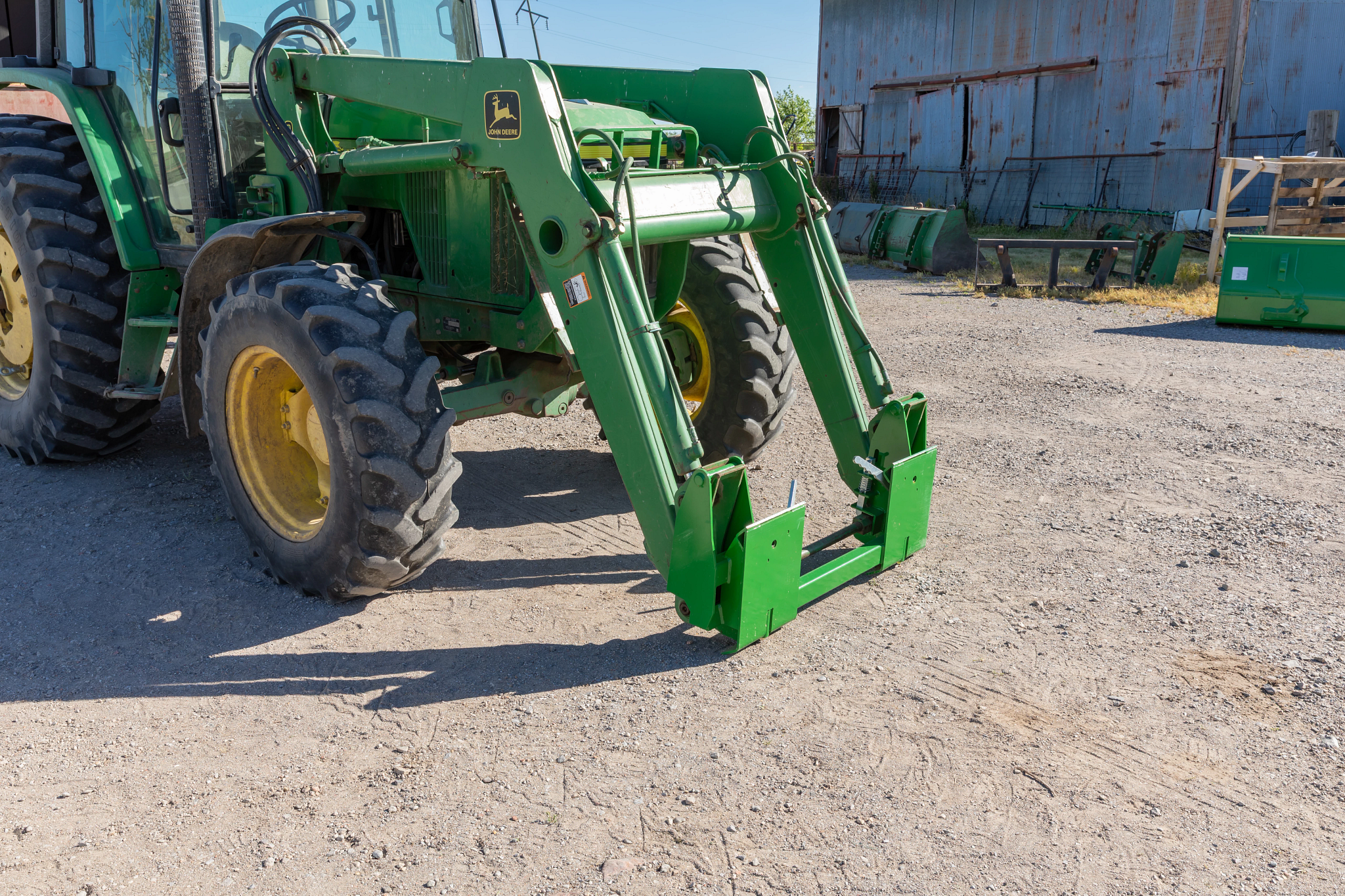 Front right view of a 6 series tractor with attached SA22D loader carrier adapter in a dirt yard