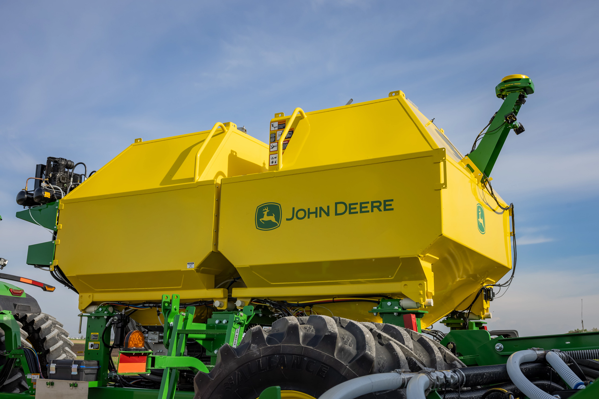 Side view of an ST16 drawn 40-ft strip till's yellow integrated fertilizer tanks, with StarFire 7000 receiver mounted on the back