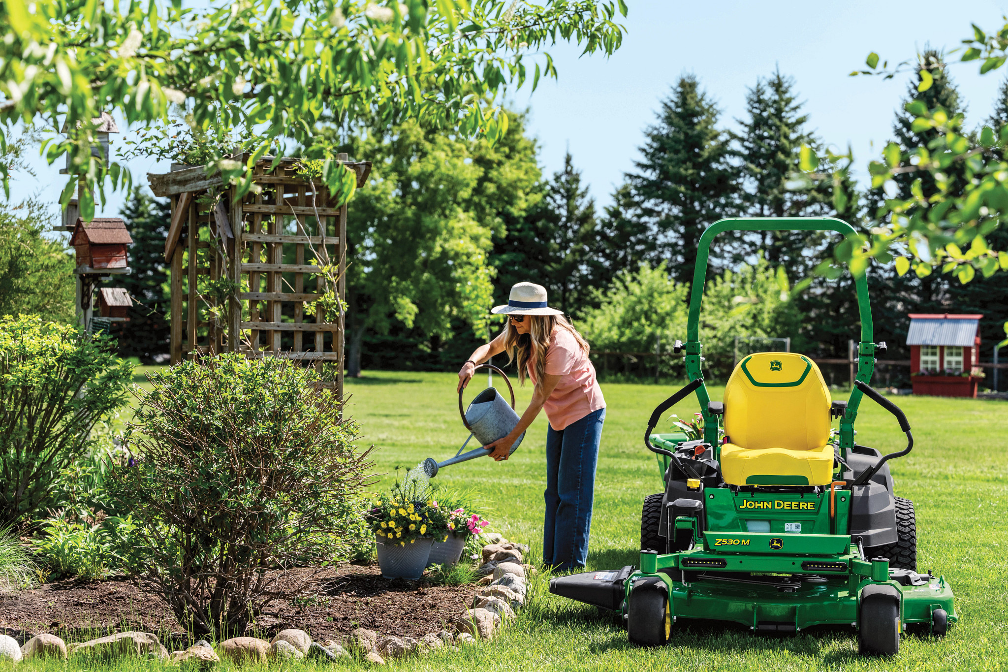 John Deere Z530M beside a homeowner tending her garden
