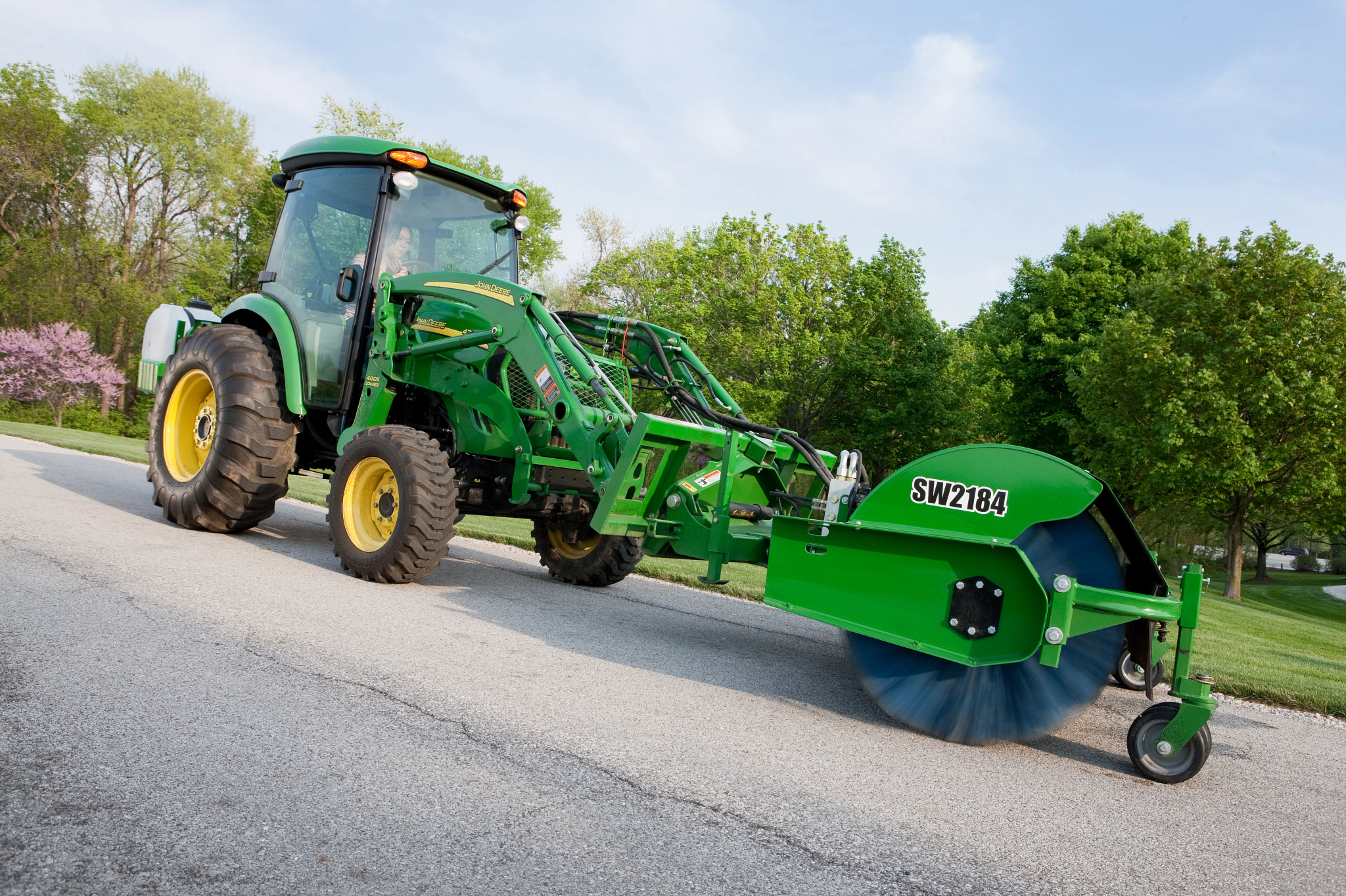 Side right view of a 400 Series Carrier Loader using a SW2184 Mount Rotary Broom along a residential road