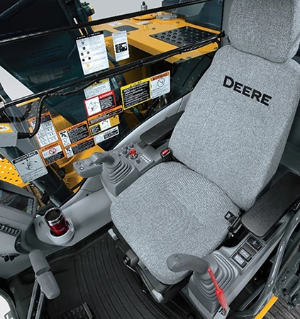 Studio view of the 200 G-Tier excavator's operator station with gray seat, joysticks, cupholder, and right-side window