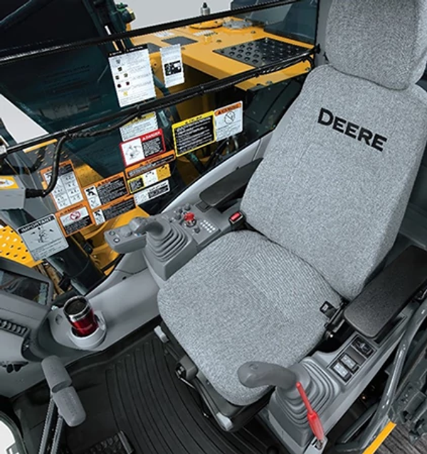 Studio view of the 200 G-Tier excavator's operator station with gray seat, joysticks, cupholder, and right-side window