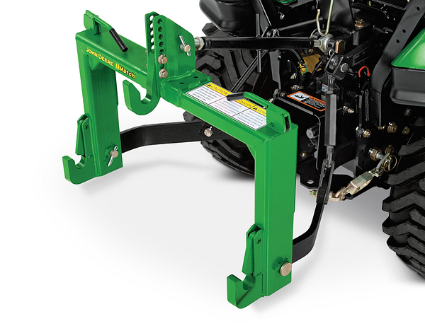 Close-up of a green rear mounting frame attached to a compact tractor, showing the steel support arms, mounting hooks, and hydraulic connections